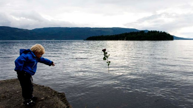 Em Sundvolden, Noruega, criança joga uma rosa no lago Tyrifjorden, em frente à ilha Utoeya, em homenagem as vítimas dos ataques da última sexta-feira