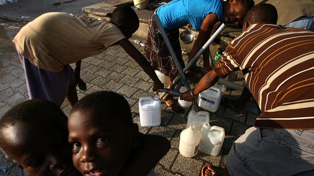 Haitianos abastecem galões com água potável