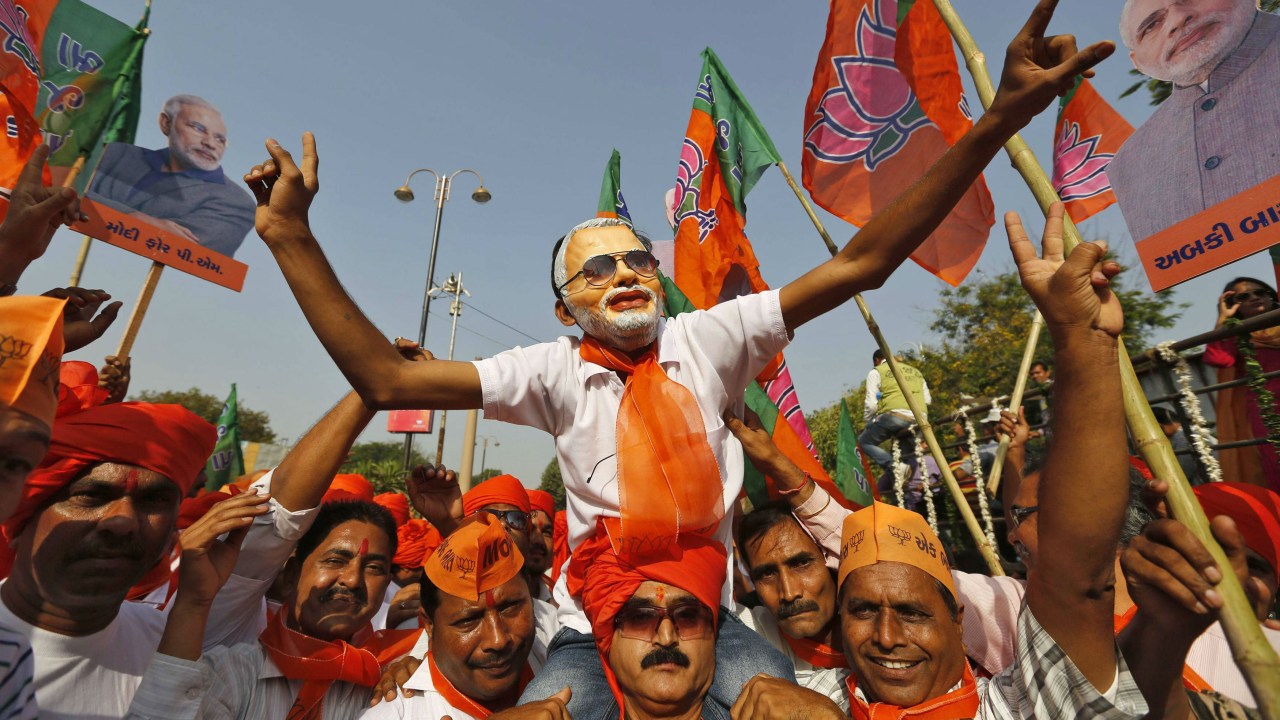 Homem com máscara do candidato Narendra Modi é carregado em Vadodara, no estado indiano de Gujarat