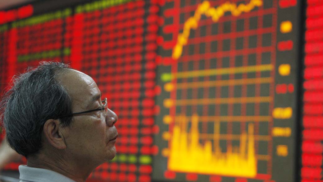 Homem observa índice eletrônico da Bolsa de Valores em Huaibei, China