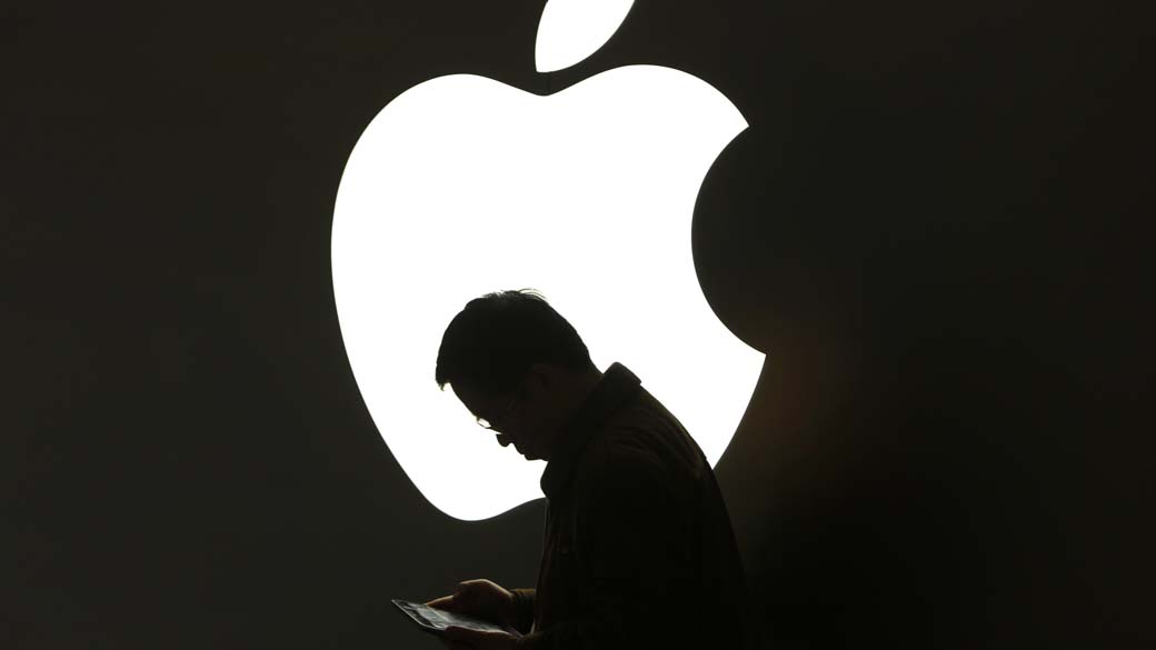Homem utiliza iPad em frente a loja da Apple em Xangai, China