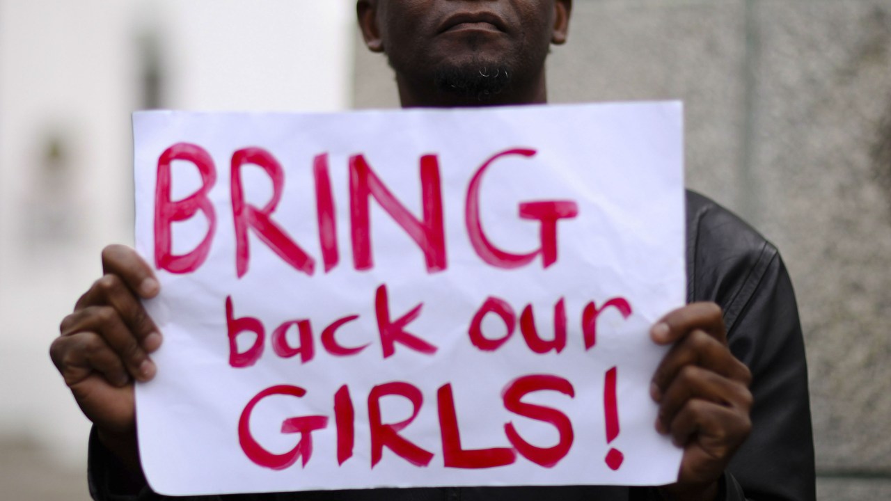 Homem segura um cartaz pedindo a libertação das meninas sequestradas pelo Boko Haram