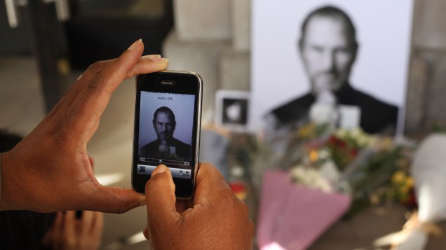 Homem fotografa tributo a Steve Jobs com um iPhone em frente a uma loja da Apple em Londres