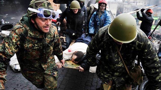Manifestantes antigovernistas socorrem um companheiro ferido durante confrontos com a polícia na praça da Independência, em Kiev (Ucrânia)