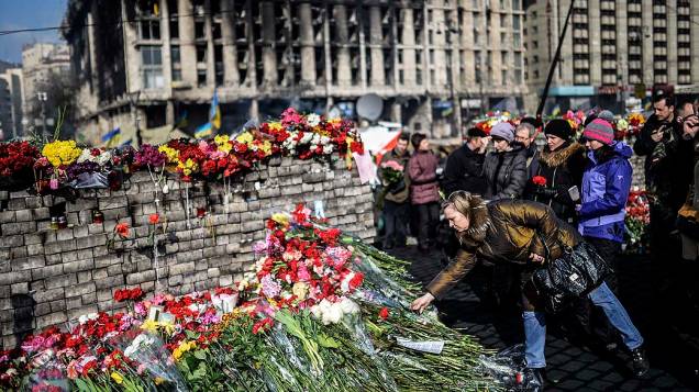 Mulher coloca flores diante de uma barricada na Praça da Independência em Kiev, nesta segunda-feira (24), homenageando os mortos nos confrontos que acabaram por derrubar o presidente ucraniano