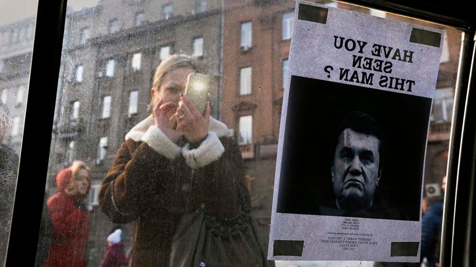 Cartaz de Procurado com a foto do presidente deposto da Ucrânia, Victor Yanukovich, colocado na janela de um carro usado como parte de uma barricada perto da Praça da Independência, em Kiev, nesta segunda-feira (24)