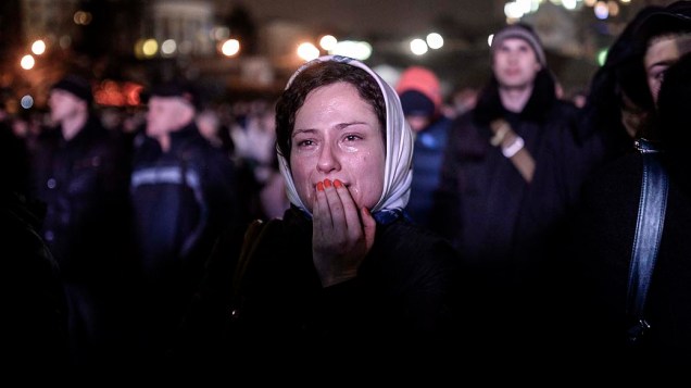 Mulher chora diante de uma barricada na Praça da Independência em Kiev, nesta terça-feira (25)