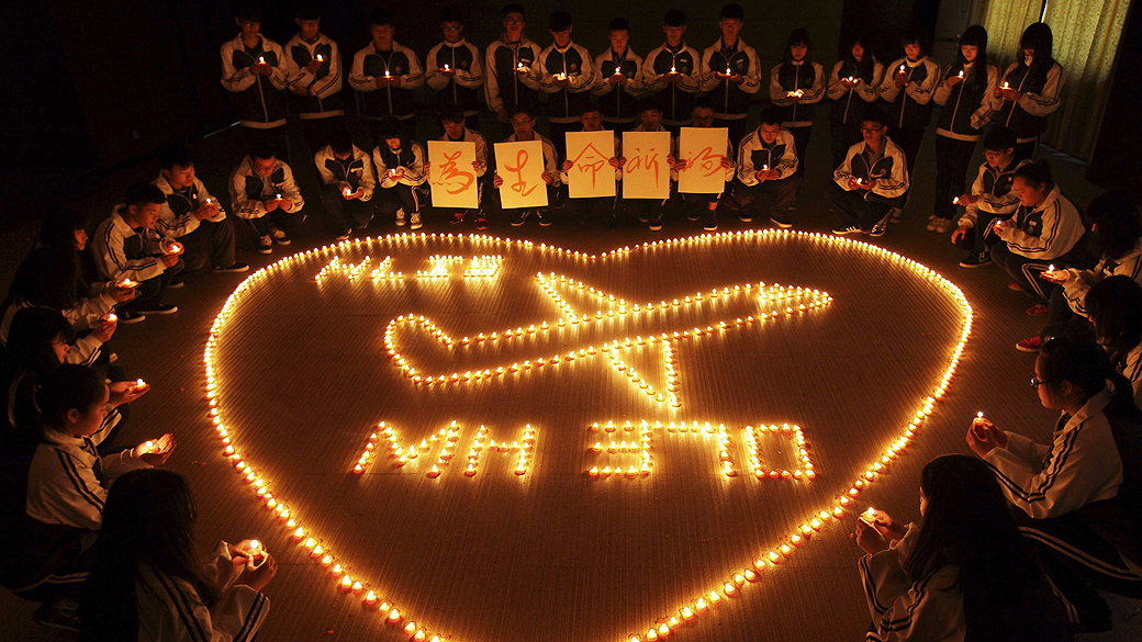 Estudantes chineses acendem velas e rezam pelos passageiros do voo desaparecido da Malaysia Airlines