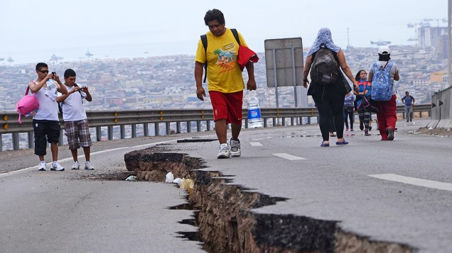 Pessoas caminham ao longo de uma estrada rachada após um novo terremoto em Iquique, norte do Chile