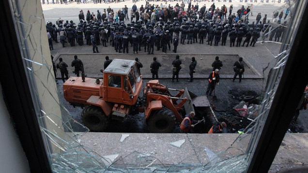 Trabalhadores limpam barricada construída por separatistas pró-Rússia em frente ao prédio administrativo de Carcóvia, na Ucrânia
