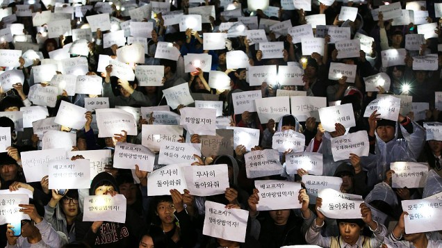 Estudantes Danwon High School seguram cartazes com mensagens para seus amigos que estão desaparecidos, após o desastre da balsa que naufragou com 475 passageiros em Jindo, na Coreia do Sul