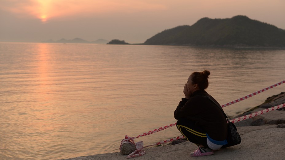 Um parente de uma vítima da balsa que naufragou na Coréia do Sul reza junto ao mar no porto de Jindo