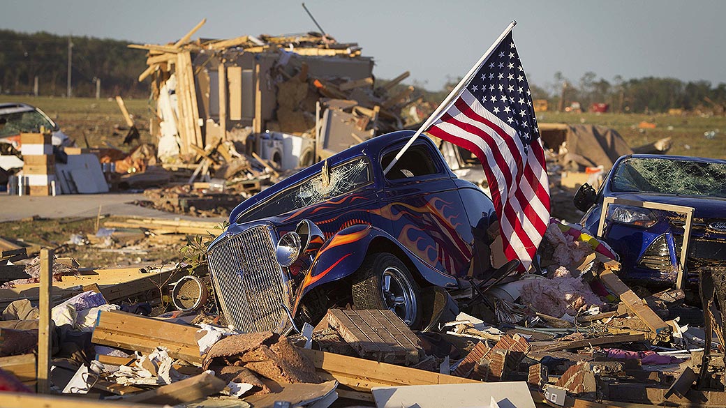 Bandeira do Estados Unidos presa à janela de um carro danificado em uma área atingida pela passagem de um tornado perto da cidade Vilonia, no Arkansas