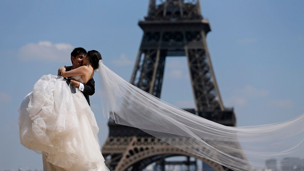 Um casal de noivos em frente à Torre Eiffel, em Paris