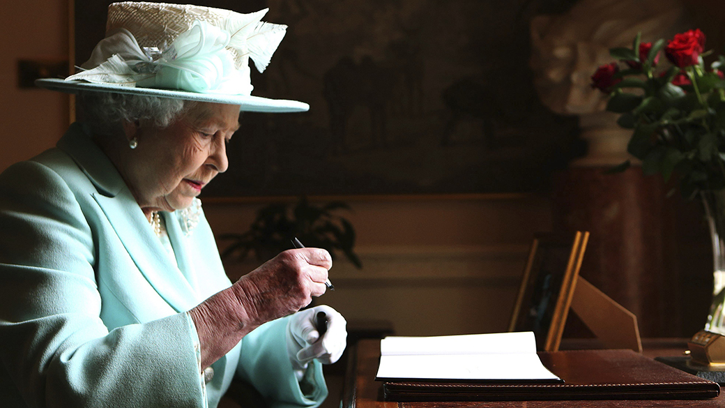 A rainha da Grã-Bretanha, Elizabeth II, escreve em seu 'Livro de visitas' durante uma passagem pela Irlanda do Norte