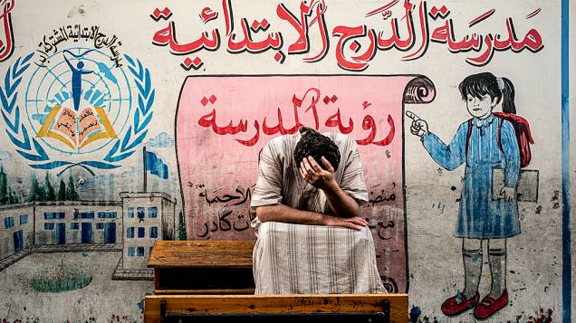 Palestino deslocado do bairro Shejaiya na Faixa de Gaza senta em um banco de uma escola administrada pela ONU, onde se juntou a outros que se refugiaram no local para fugir dos pesados combates ​​em sua área