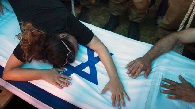 A mãe de soldado israelense chora sobre a bandeira nacional durante funeral do filho, em Rishon Lezion, região próxima a Tel Aviv. Israel abateu alvos em toda a Faixa de Gaza nesta terça-feira (22), contrariando pressões de diplomaciais internacionais para um cessar-fogo iumediato na região. Os conflitos já fizeram mais de 500 mortos entre pelestinos e israelenses