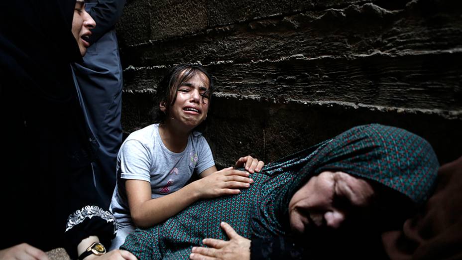 Parentes de um palestino de 60 anos morto após ataques do exército israelense, choram durante seu funeral na cidade de Gaza