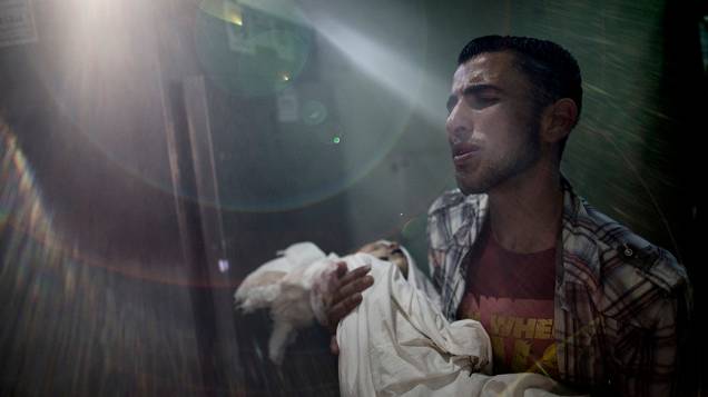 Pai segura o corpo do filho morto por estilhaços de um tanque israelense, no hospital Kamal Adwan, ao norte da Faixa de Gaza, em 24/07/2014. O Secretário de Estado norte-americano, John Kerry, declarou que os esforços globais para acabar com 16 dias de conflito na região devem continuar