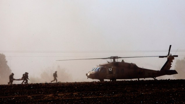 Israelenses carregam um soldado ferido para um helicóptero, perto da fronteira com a Faixa Gaza, nesta quinta-feira (24). Os conflitos se intensificaram na região há três semanas, e o número de mortos já passa de 600