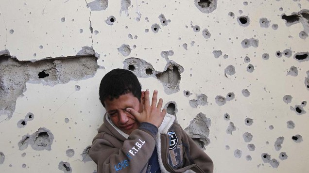 Garoto chora em sua casa danificada pelos ataques israelenses, em Gaza