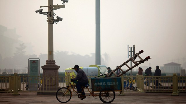 Trabalhador anda num triciclo, na província chinesa de Henan, em dia de forte neblina, agravada pela poluição do país