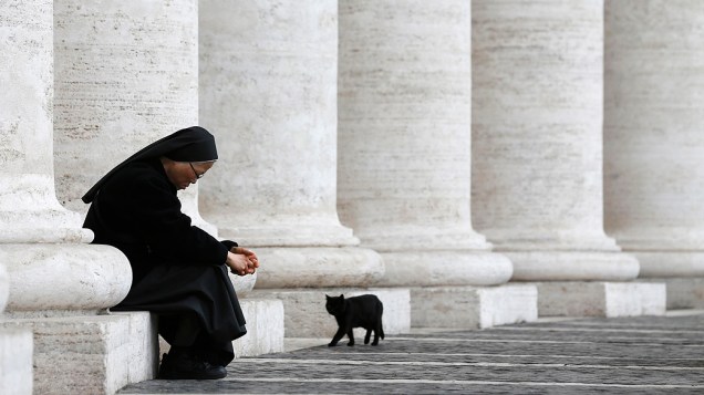 Gato preto caminha ao lado de freira na Praça de São Pedro, no Vaticano