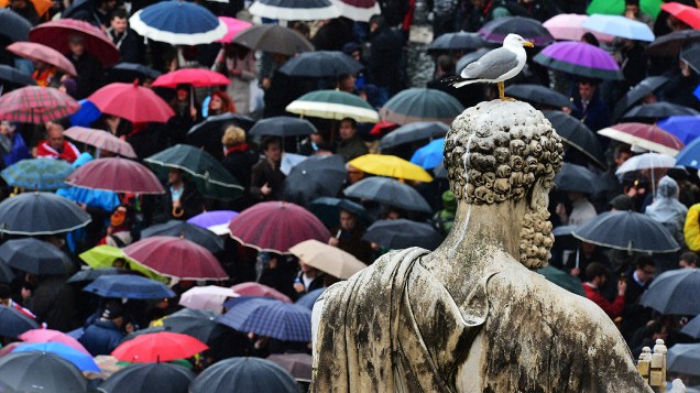 Sob chuva, os fiéis esperam na Praça de São Pedro o possível anúncio do novo Papa