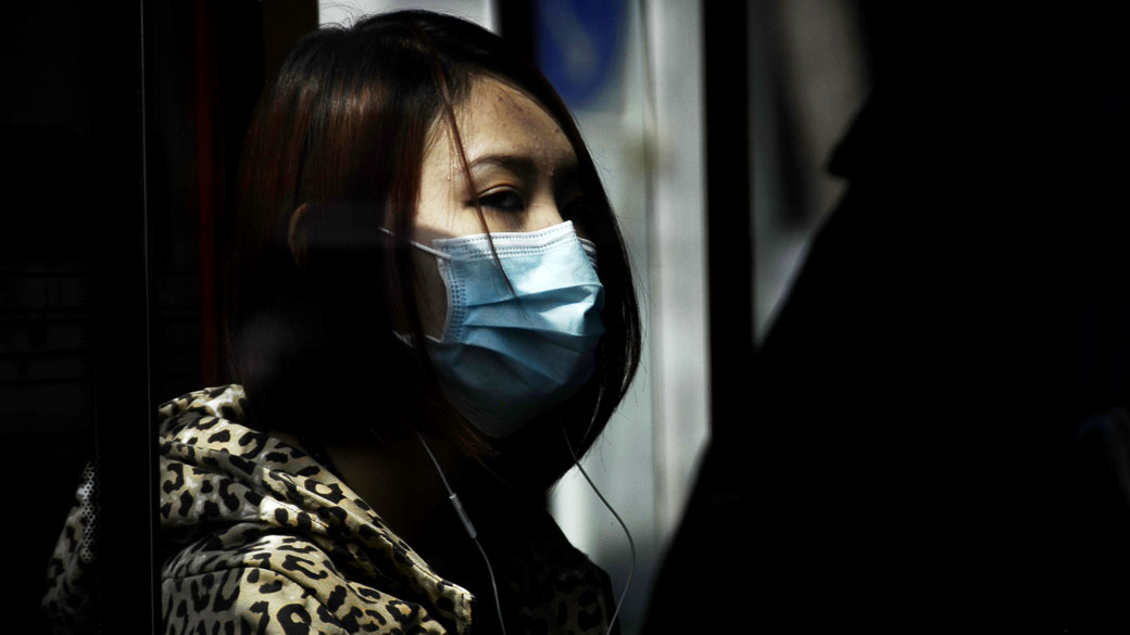 Mulher usa máscara em um ônibus de Pequim devido a epidemia de gripe aviária H7N9