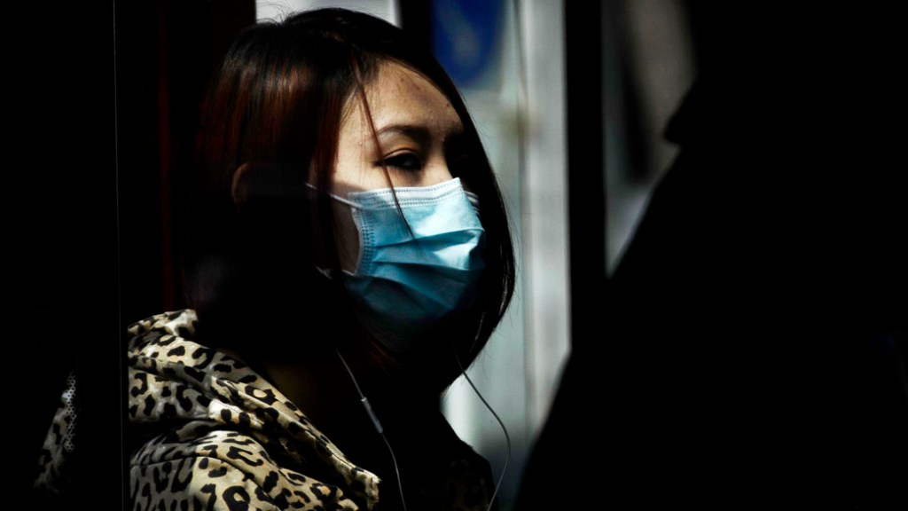 Mulher usa máscara em um ônibus de Pequim devido a epidemia de gripe aviária H7N9