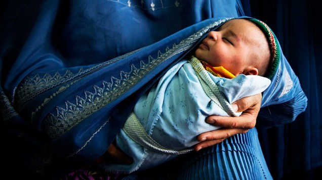 Mulher afegã segura bebê recém-nascido no centro antigo de Cabul (Afeganistão)