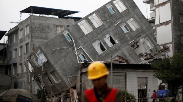 Homem presta socorro na frente de um prédio danificado após o terremoto na cidade Lingguan de município de Baoxing, da província de Sichuan. O terremoto foi o pior dos últimos três anos,  com 208 mortos e  com quase 1.000 feridos graves, na China
