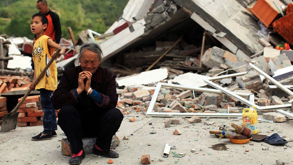 Idosa chora ao lado de sua casa destruída na cidade de Ya'an, no sudoeste da China