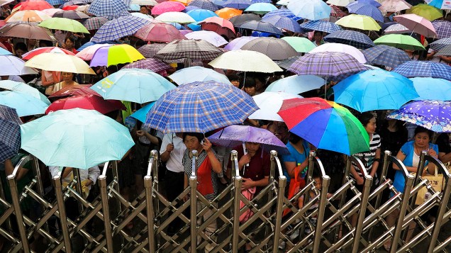 Sob chuva, centenas de pais esperam longas horas pela saída dos filhos das salas de exame