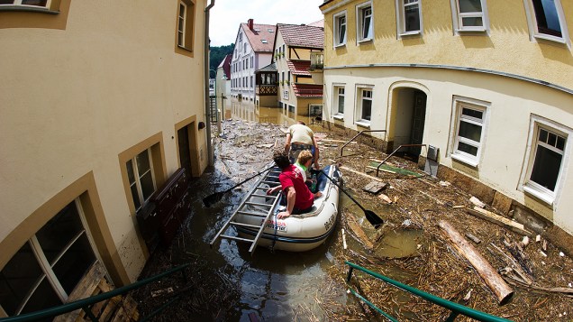 Alemães cruzam com bote rua de Stadt Wehlen alagada após fortes chuvas