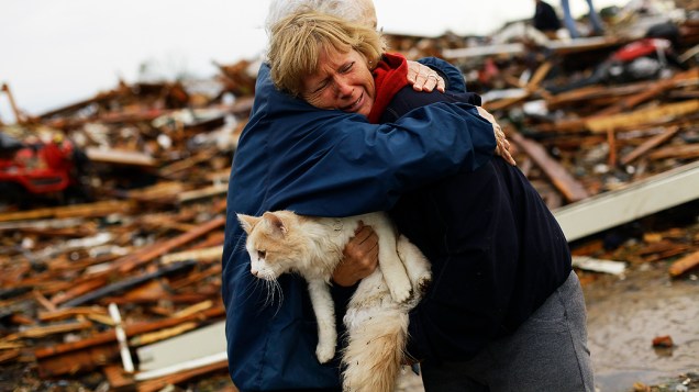 Mulher com seu gato diante de área devastada por tornado no distrito de Moore, em Oklahoma