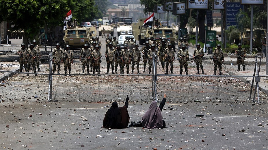 Apoiadores do presidente deposto do Egito, Mohamed Morsi, sentam em frente a barreira de arame farpado que bloqueia o acesso à Guarda Republicana no Cairo