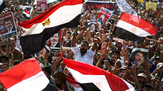 Apoiadores do presidente deposto do Egito, Mohamed Morsi, empunham bandeiras e cartazes a seu favor, próximo à Guarda Republicana no Cairo nesta segunda-feira (8)