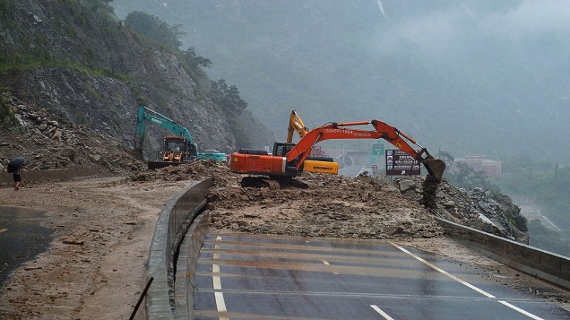 Trabalhadores usam escavadeiras para limpar a estrada bloqueada por deslizamentos de terra causadado pelas fortes chuvas em Wenchuan, China