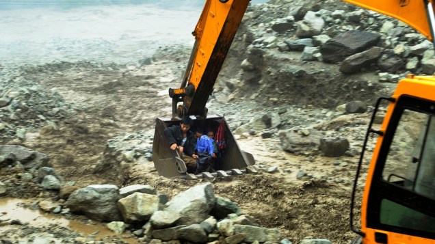 Uma escavadeira retira moradores de uma área alagada durante as fortes chuvas nesta quinta-feira (11), em Yingxiu, província de Sichuan, China