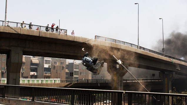 Um veículo da polícia é empurrado para fora da ponte 6 de outubro por manifestantes partidários do presidente deposto Mohammed Mursi, no Cairo, nesta quarta-feira (14)