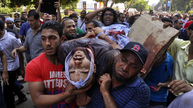 Manifestantes carregam homem ferido durante os protestos no Cairo, nesta sexta-feira (16)