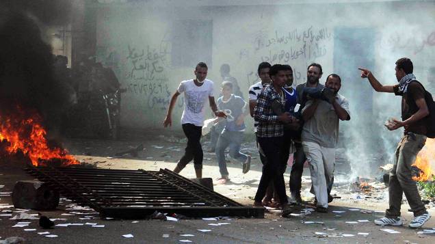  Manifestantes ajudam pessoas feridas durante os confrontos no Cairo, nesta sexta-feira (16)