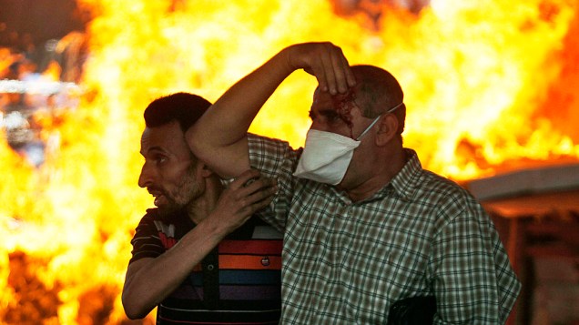 Manifestantes ajudam pessoas feridas durante os confrontos no Cairo, nesta sexta-feira (16)