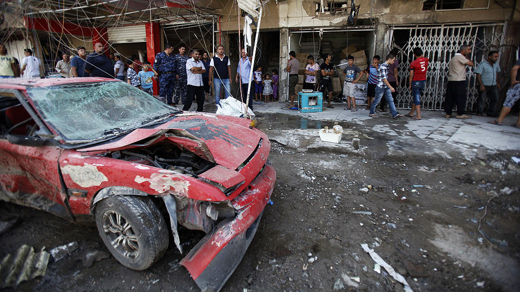 Pessoas se reúnem no local onde um carro-bomba explodiu em Bagdá. O número de mortos em uma série de atentados e ataques em toda Bagdá foi de pelo menos 44 pessoas e dezenas de feridos, no Iraque