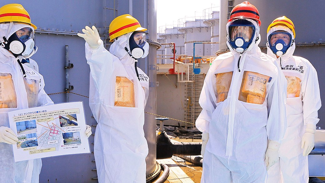 O primeiro-ministro do Japão, Shinzo Abe, usa roupa de proteção e máscara, durante visita aos tanques contendo água radioativa da usina nuclear de Fukushima, nesta quinta-feira (19)