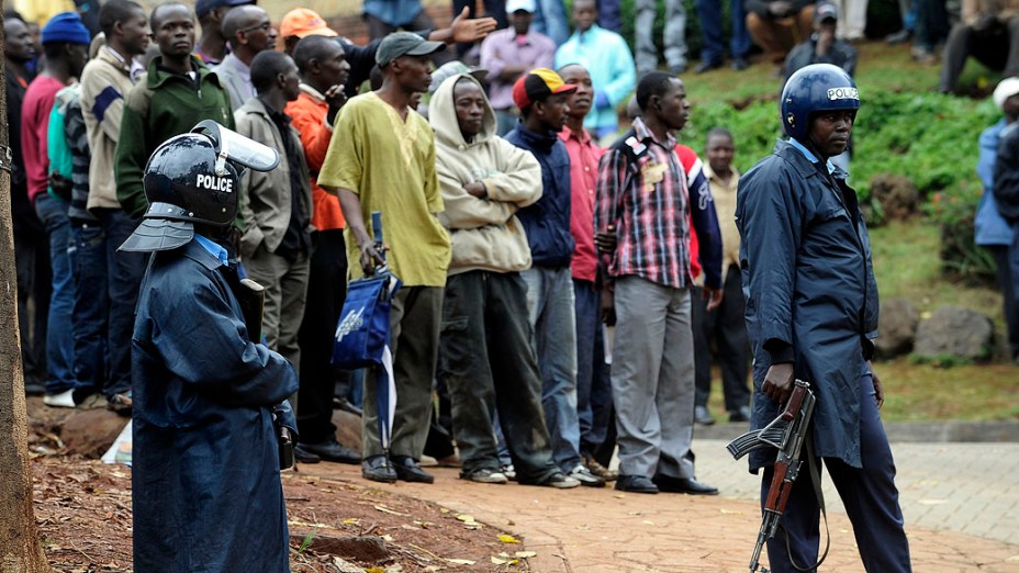 Policiais afastam as pessoas do lado de fora do shopping Westgate em Nairobi. A policia entrou em um tiroteio com os militantes da milícia islâmica Al-Shabab dentro de um shopping de luxo Nairobi em 22 de setembro em um último esforço para acabar com o cerco que deixou pelo menos 69 mortos e 200 feridos, no Quênia