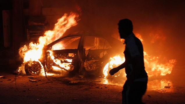 Homem olha para um carro em chamas no local de um atentado a bomba em Bagdá nesta segunda-feira (07). Diversos atentados ocorreram em toda a capital iraquiana dezenas de mortos