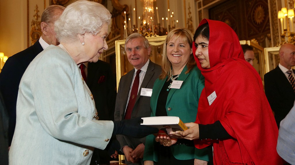 A jovem ativista paquistanesa Malala Yousafzai entrega uma cópia de seu livro para a rainha