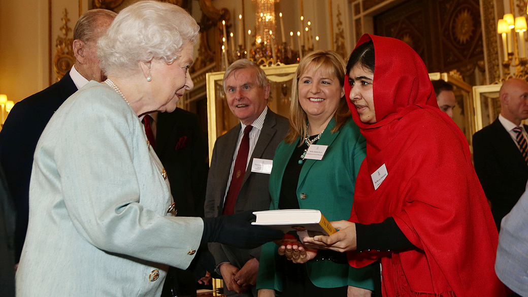 A jovem ativista paquistanesa Malala Yousafzai entrega uma cópia de seu livro para a rainha